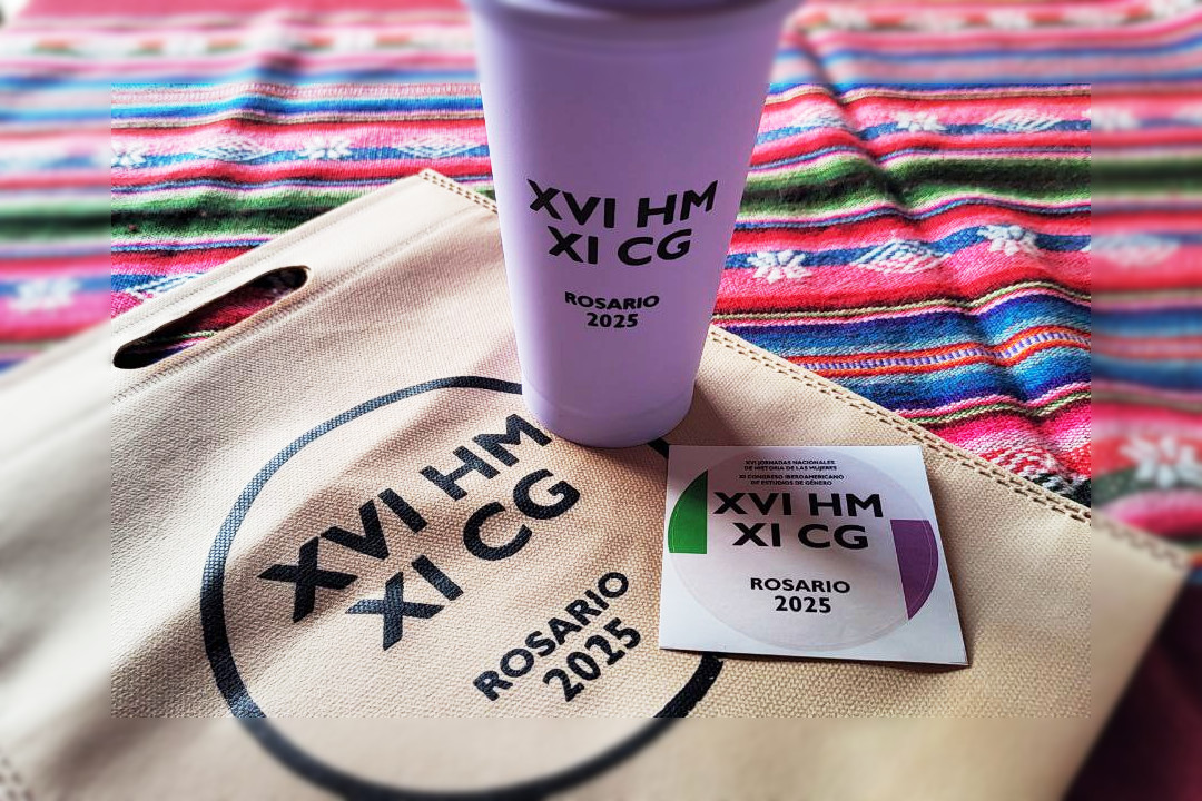 Vaso plástico, bolsa de tela y sticker, apoyados sobre una mesa. Los tres elementos tienen impreso el logo del evento.